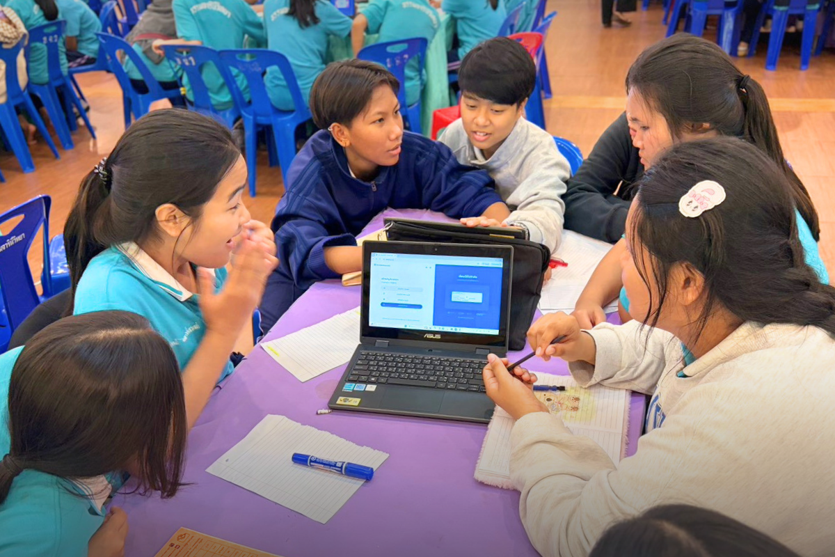 Students gather around a laptop to try the platform together